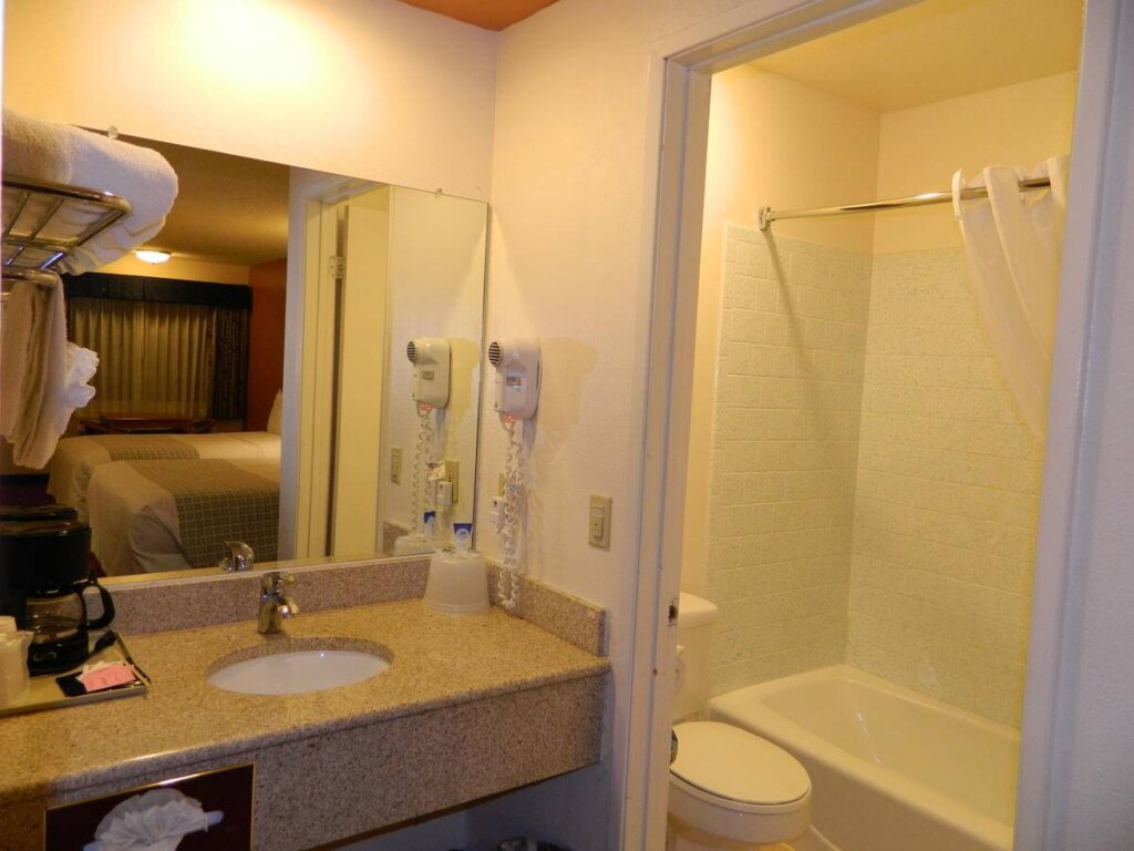 Shower, sink, and counter of a SLO INN room bathroom.