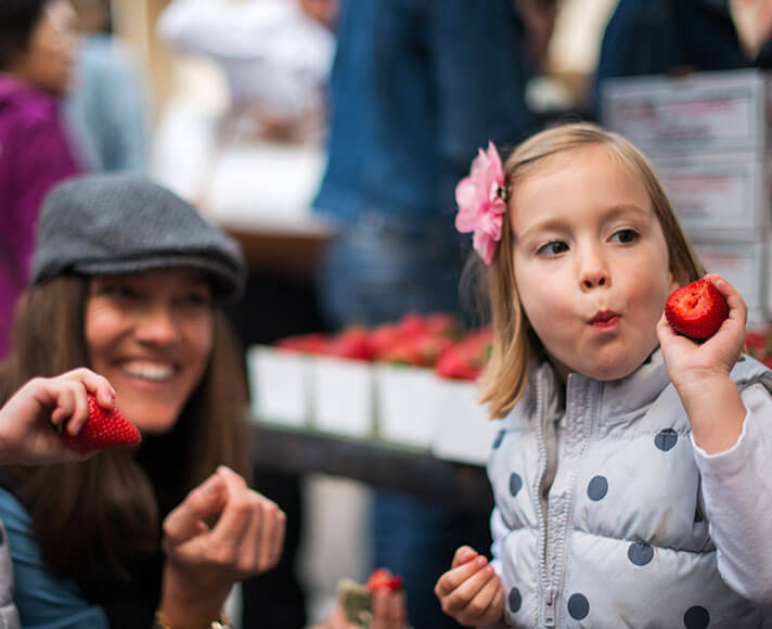 Kids enjoying strawberries at the family friendly farmer's market in San Luis Obispo