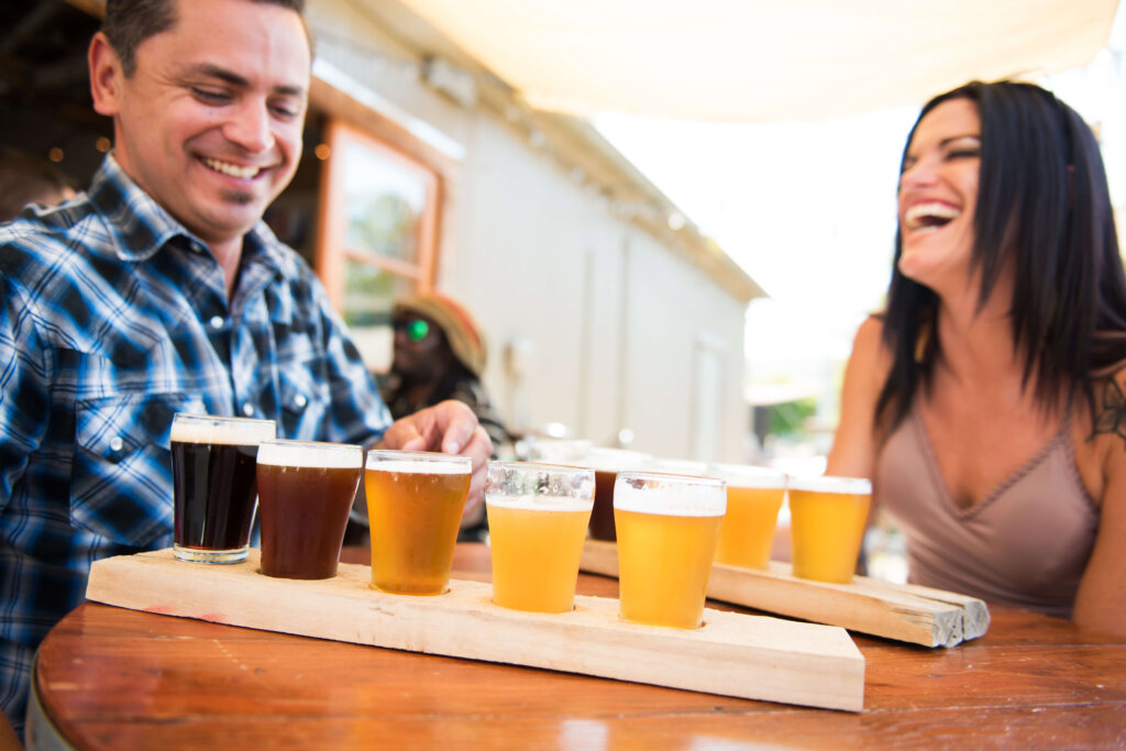 A man and woman with beer flight samplers from Bang the Drum Brewery in San Luis Obispo.