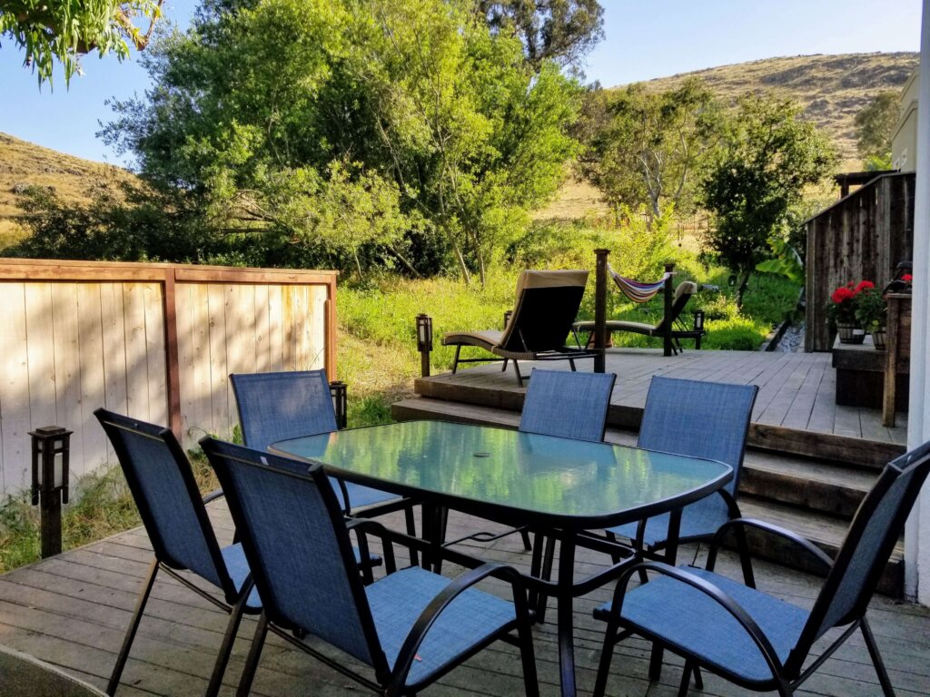 Bluerock Retreat Homestay Backyard patio with chairs around a dining table among the trees of San Luis Obispo.