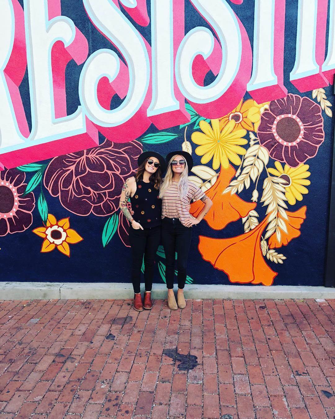 2 smiling ladies in front of the San Luis Obispo mural reading, "SLO Irresistible." Photo by @sarah_tracy