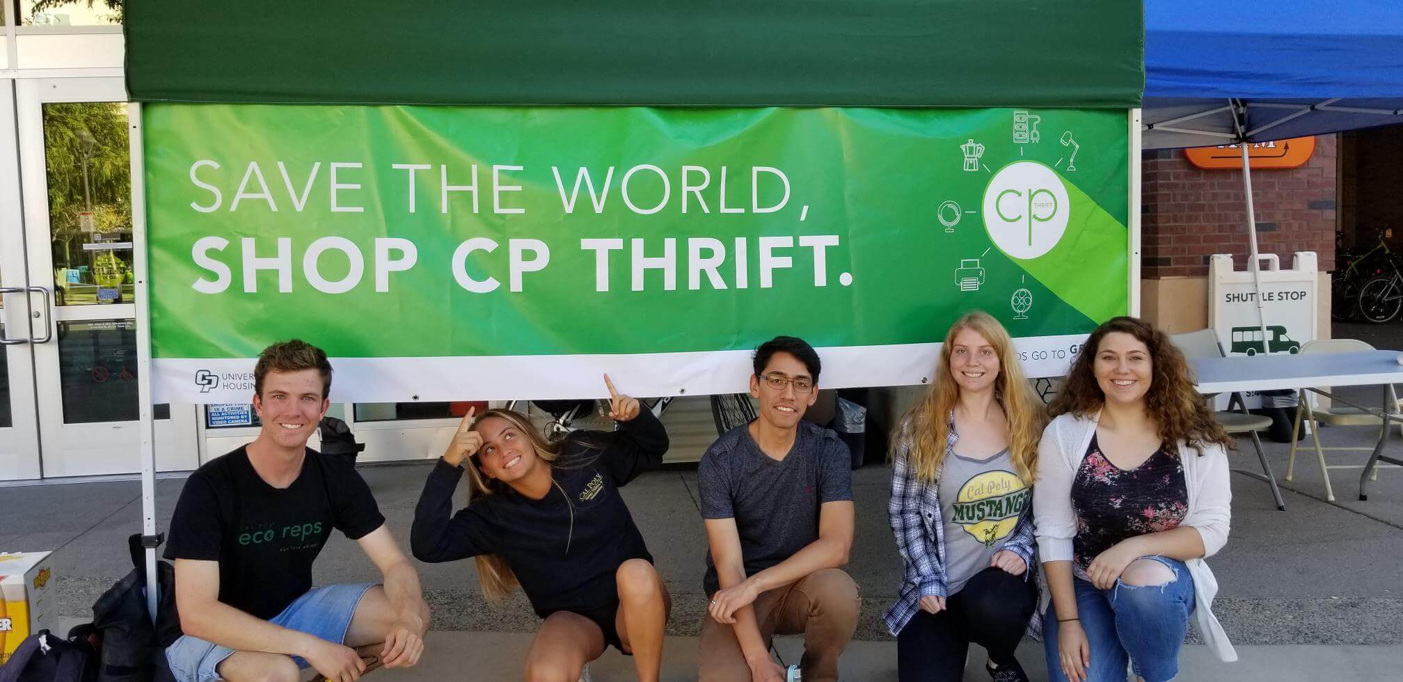 6 Cal Poly Students crouching in front of a CP Thrift green Banner.