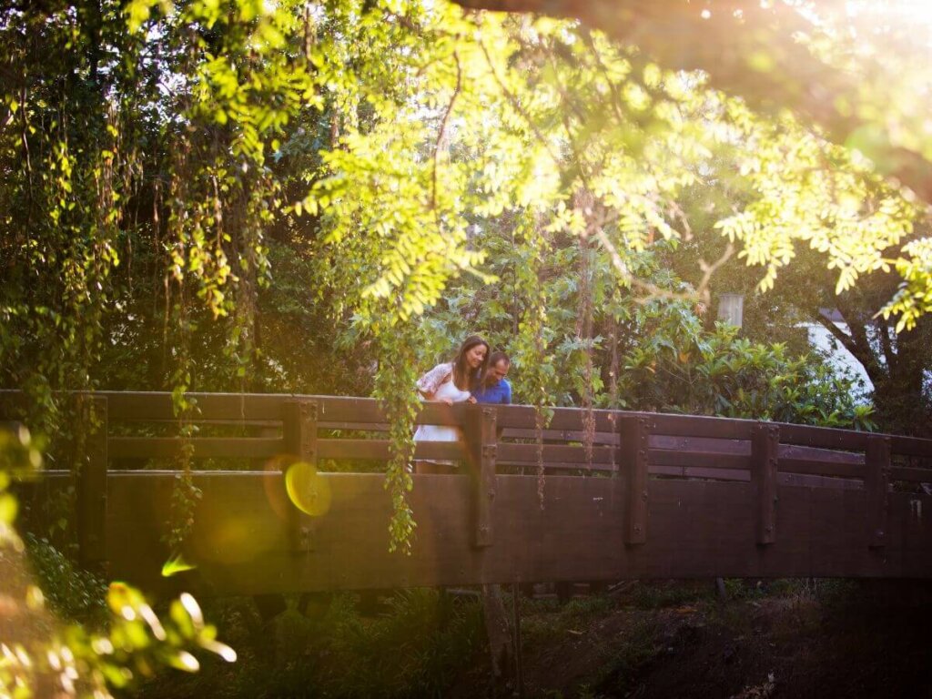 A couple looking over the shaded bridge at the San Luis Obispo Creek