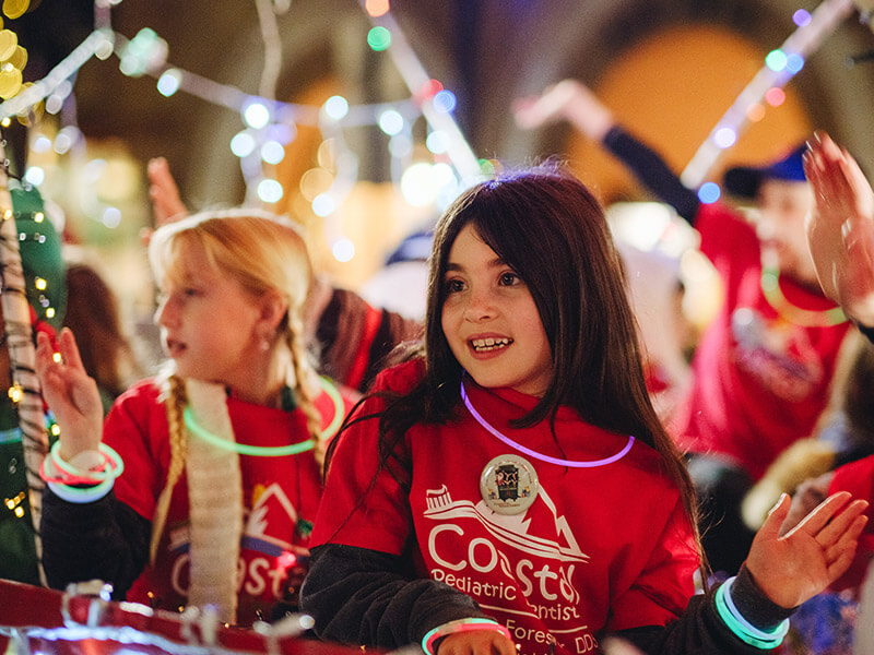 Two smiling girls in christmas sweaters at the San Luis Obispo Holiday Parade