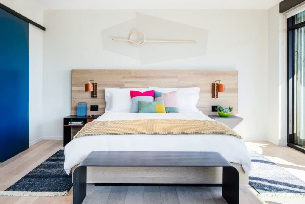 A clean, single bed with white sheets surrounded by modern fixtures in a Hotel San Luis Obispo room