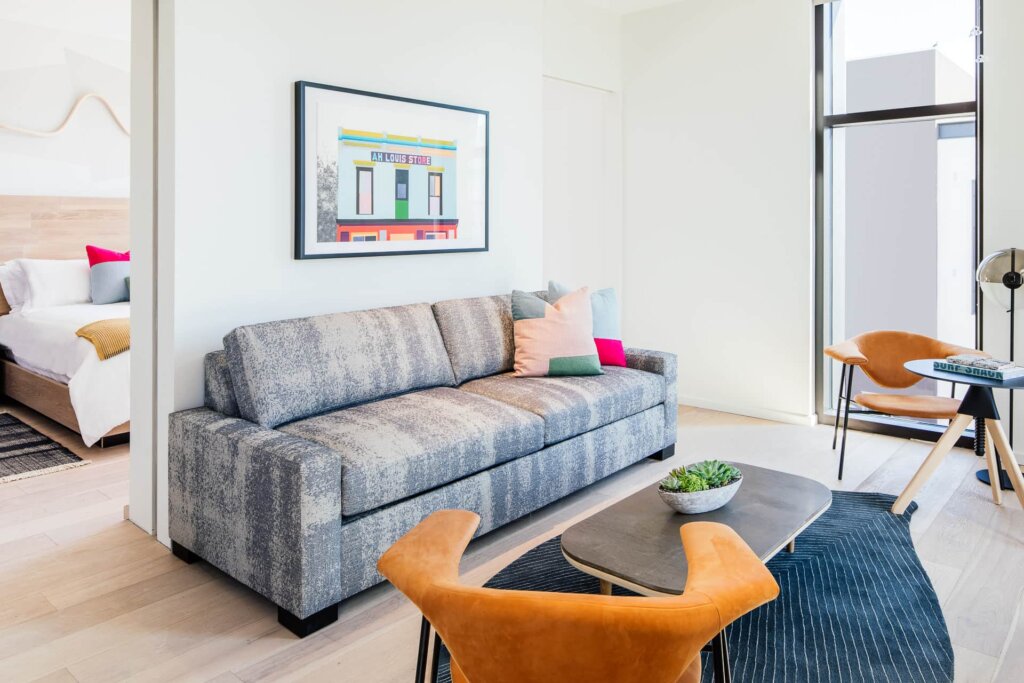 A white-walled, colorfully decorated sitting area, opposite a bedroom in a Hotel San Luis Obispo suite