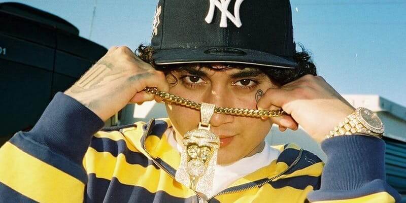 Artist Ohgeesy with a Yankees hat, gold Jesus chain, and striped shirt.