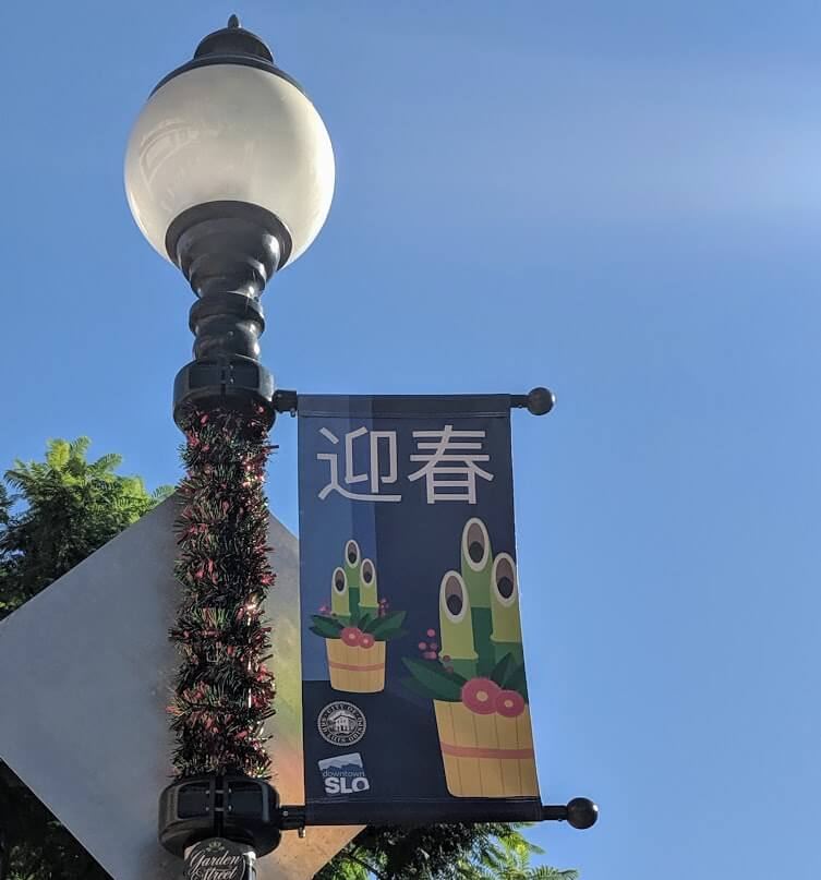 A downtown San Luis Obispo street lamp with a Omisoka banner.