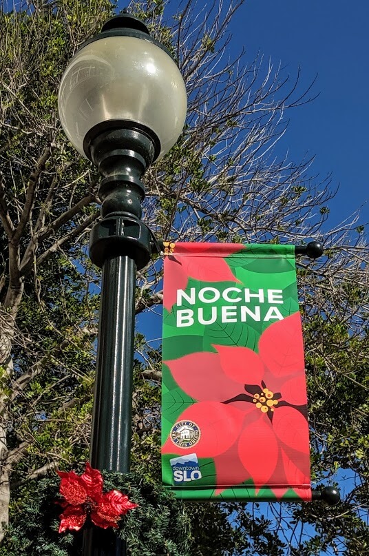 A downtown San Luis Obispo street light with a banner that says, "Noche Buena."