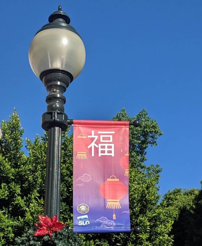 A downtown San Luis Obispo street light with a holiday banner celebrating Chinese New Years.