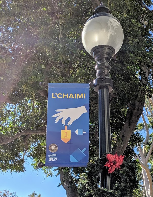 A downtown San Luis Obispo street light with a banner celebrating Hanukkah.