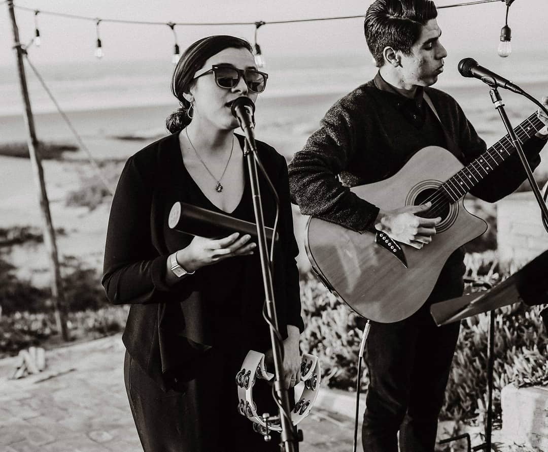 Elias and Madeline singing and playing guitar, dressed in black.