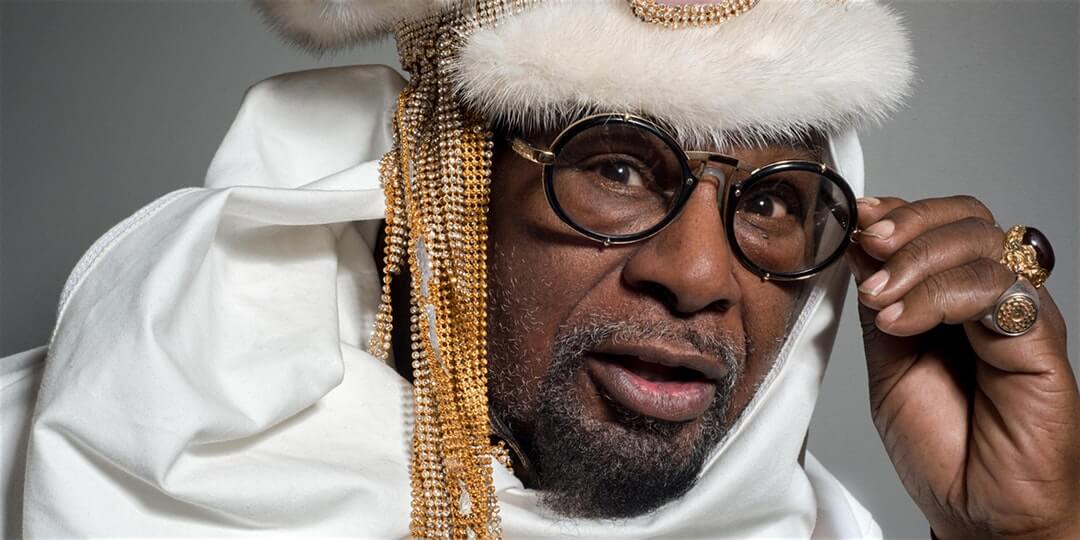 George Clinton portrait in white clothing with thick-framed glasses.