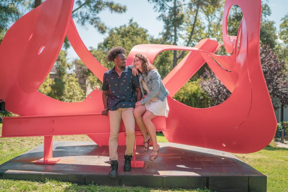 couple standing in front of red sculpture
