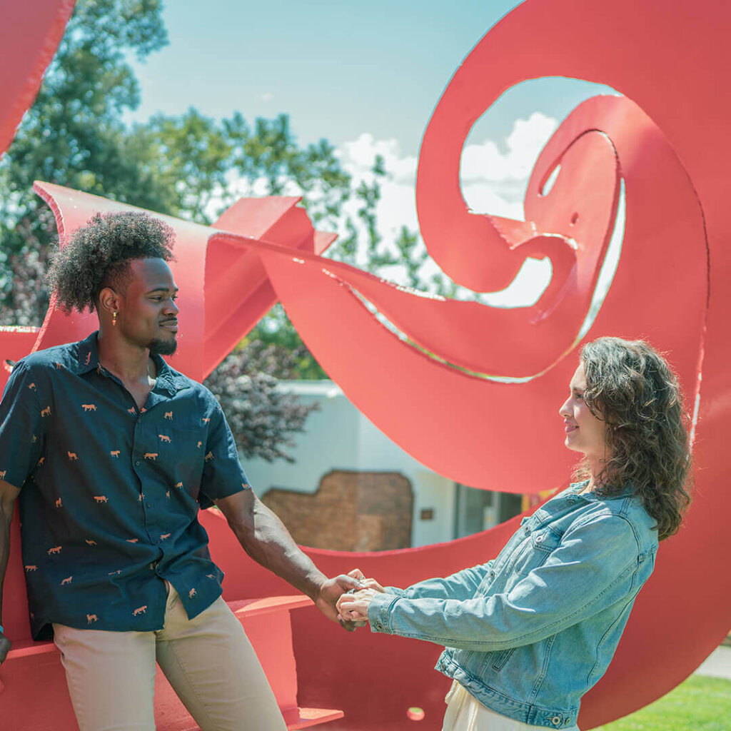 a couple plays near a sculpture in San Luis Obispo