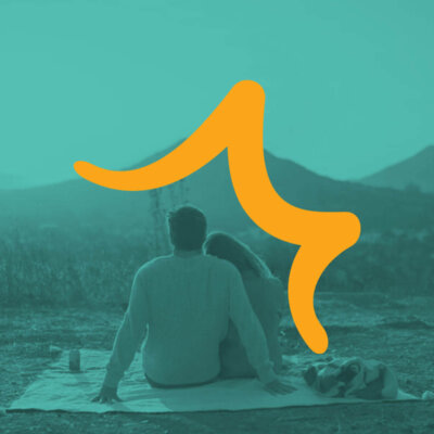 Couple sitting with a dog on a blanket overlooking SLO hills with Visit SLO logo overlay