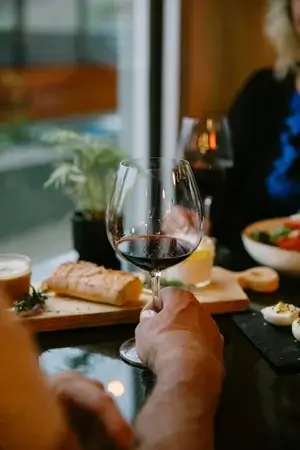 glass of red wine being held on the table